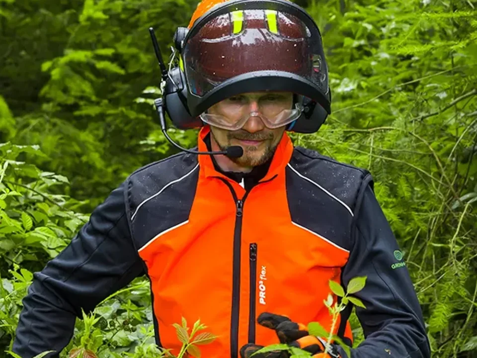 Forstarbeit in orangener Kleidung und Forsthelm läuft